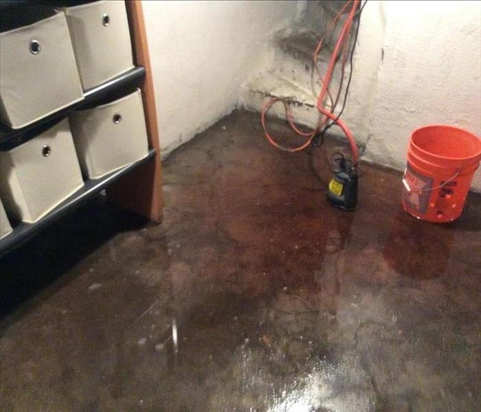 Flooded basement  with a orange bucket on the right 