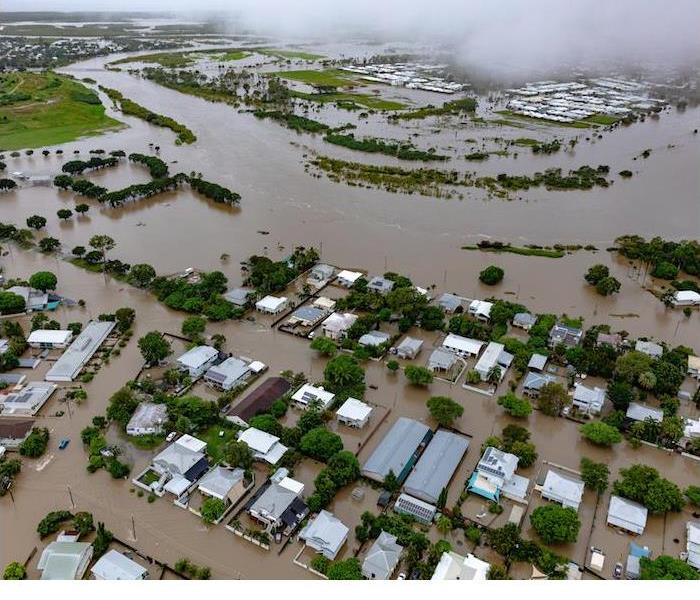 Overhead perspective of a flooded community, featuring waterlogged homes and swamped roads.