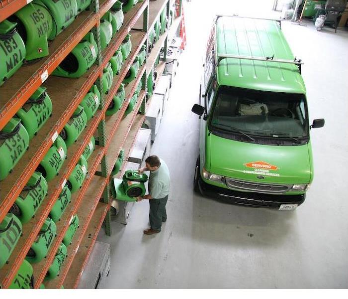 A green SERVPRO van parked in a warehouse full of equipment