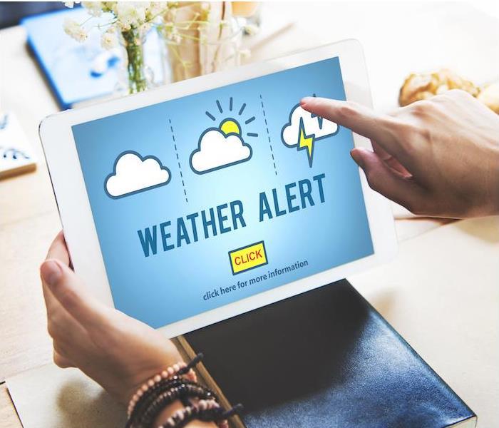 person on a white tablet using weather alert app